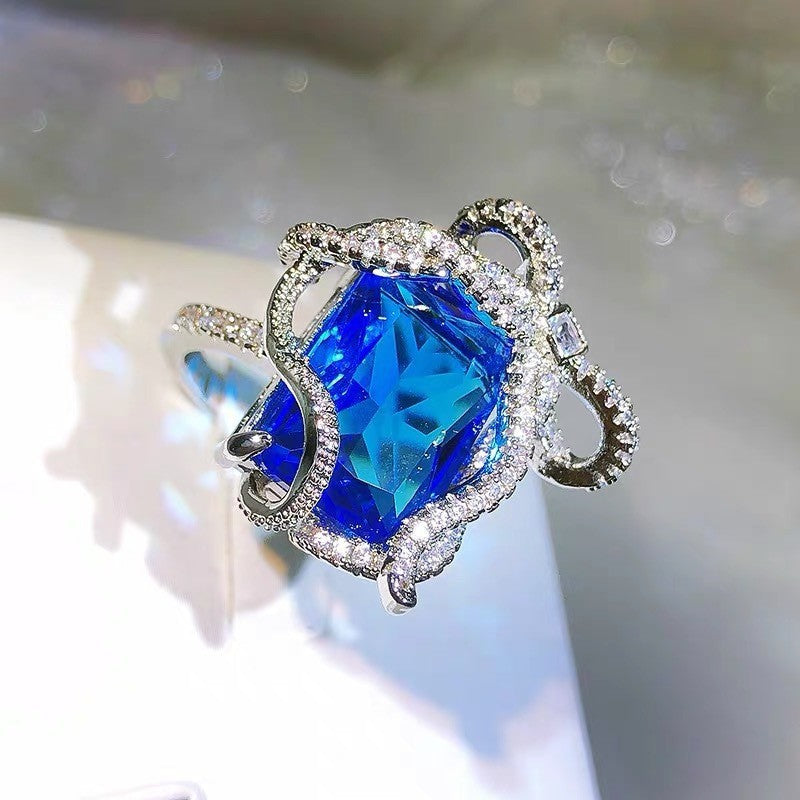 Ring with a blue gemstone and silver setting on a blurred background